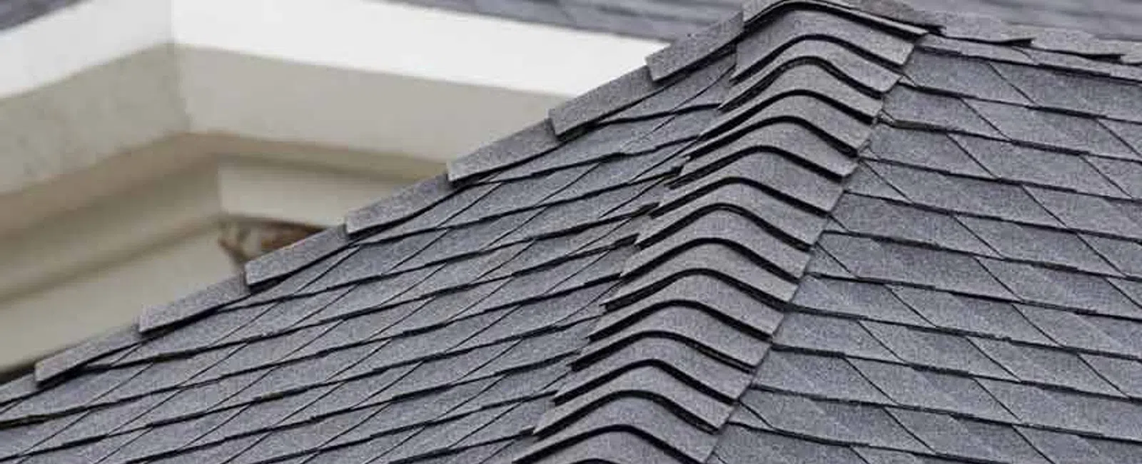 Close-up of dark gray asphalt shingle roofing with clean, overlapping rows on a residential roof.