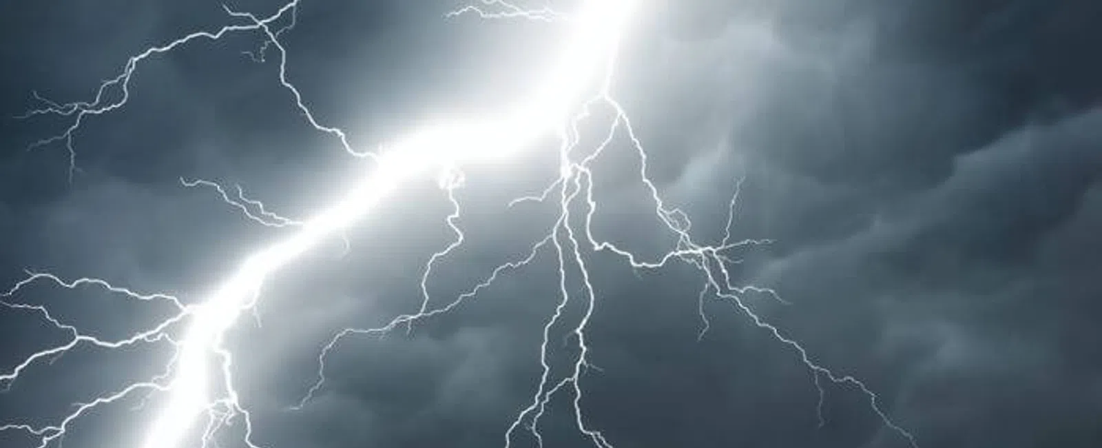 Bright lightning bolt striking through dark, stormy clouds against a gloomy sky, capturing a powerful thunderstorm moment.