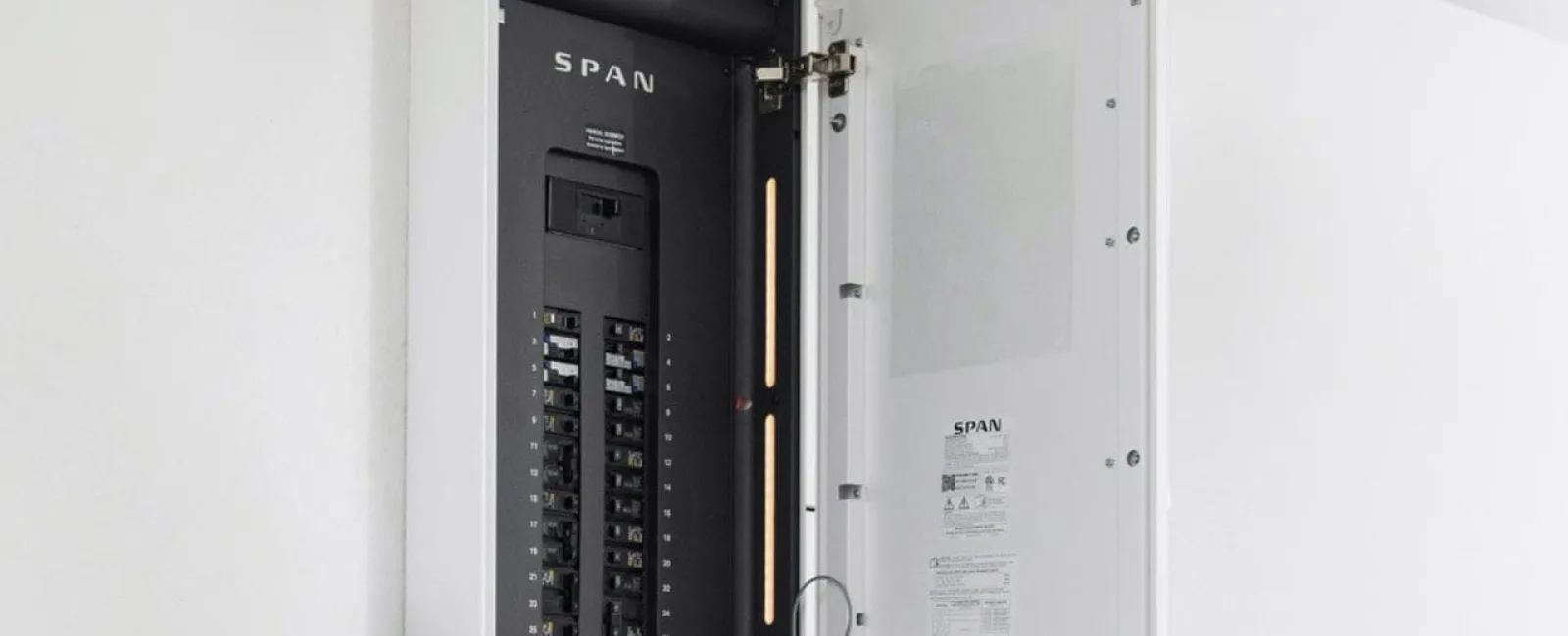 Open SPAN electrical panel with switches and circuit breakers mounted on a white wall