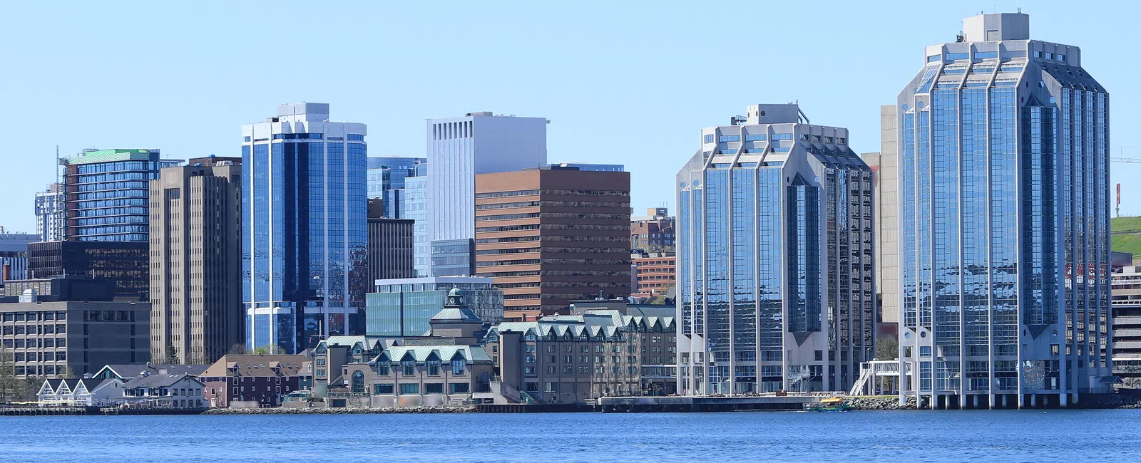 Halifax skyline with modern skyscrapers and waterfront under clear blue sky and calm water.