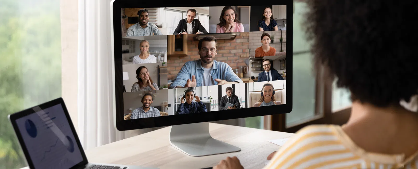 Person attending a virtual meeting on desktop with multiple colleagues visible in the video conference grid.