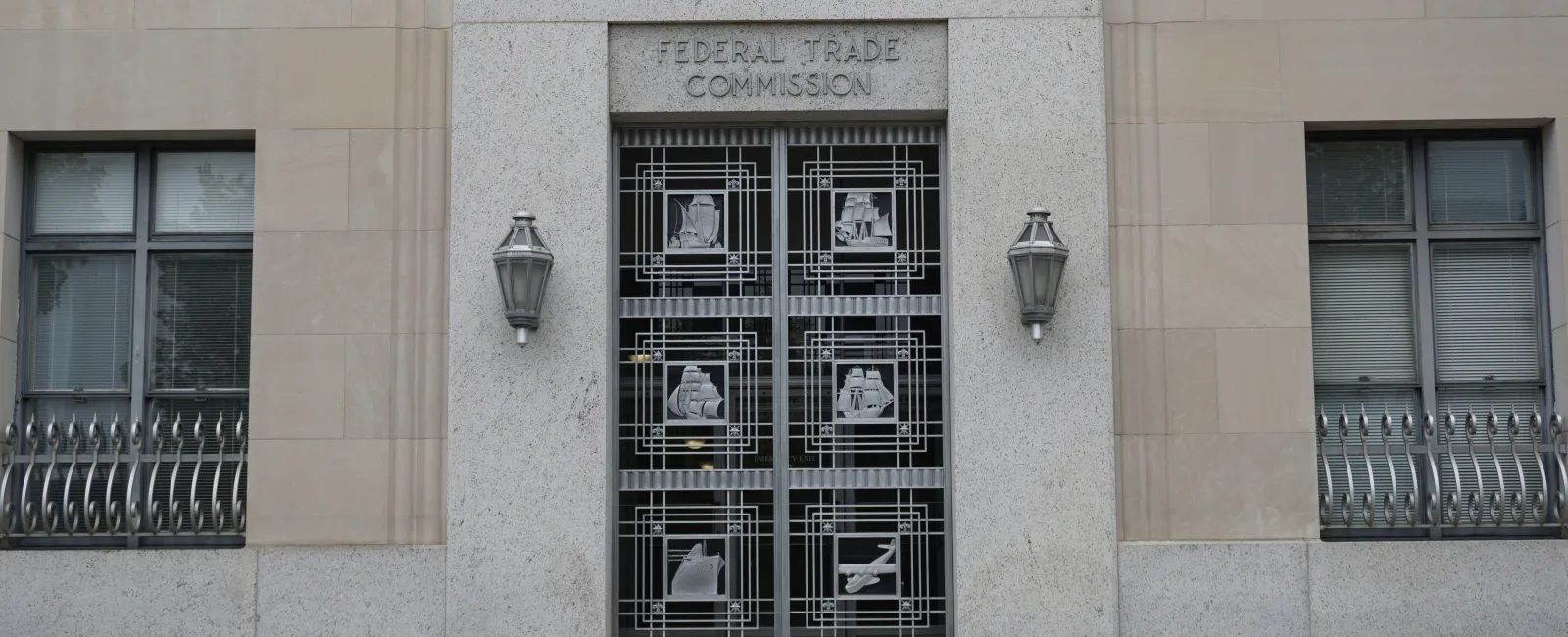 Entrance to the Federal Trade Commission building with decorative metal doors and stone facade.