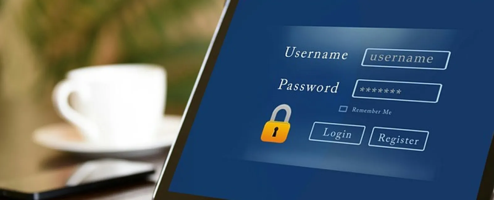 Tablet displaying login screen with username and password fields on wooden table with coffee cup and phone.