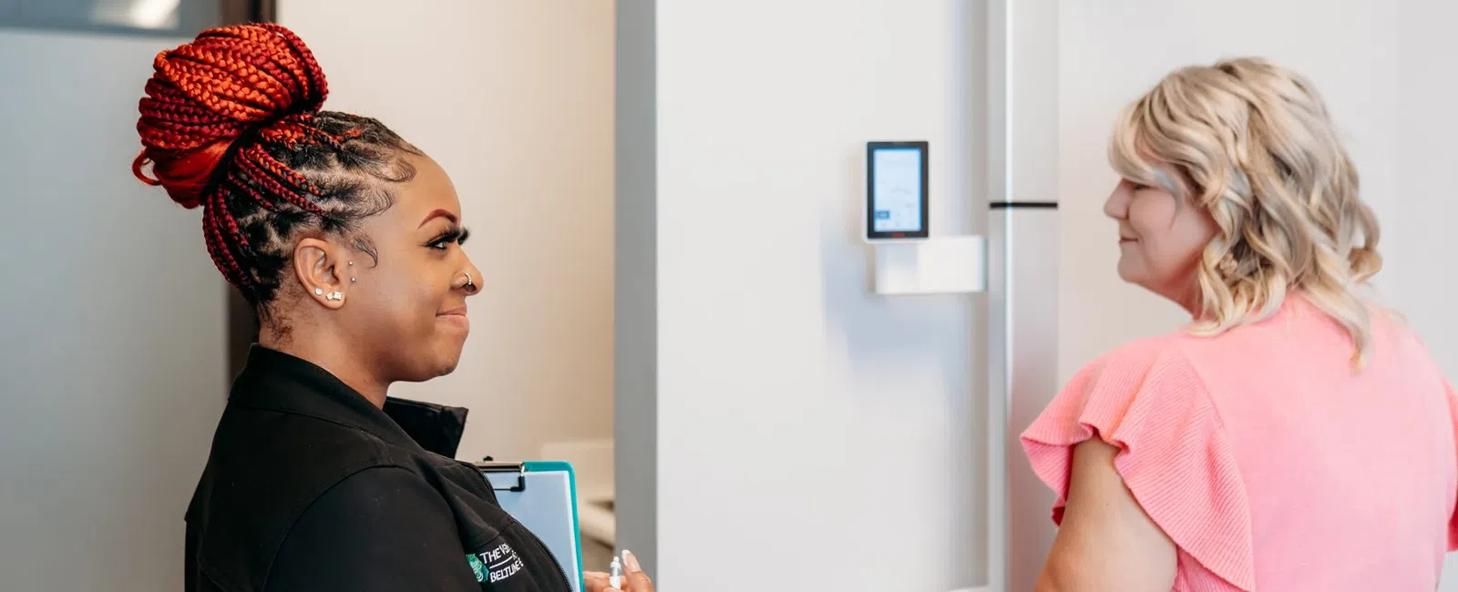 A Beltline Health staff member talking with a patient beside a body composition analyzer during a weight loss visit