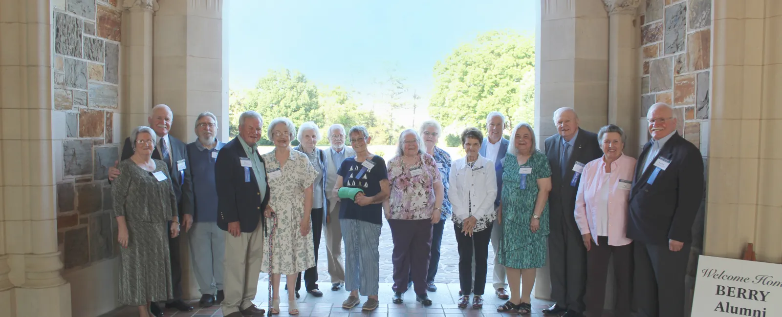 Group of Berry College alumni standing under an archway during a reunion event on a sunny day.