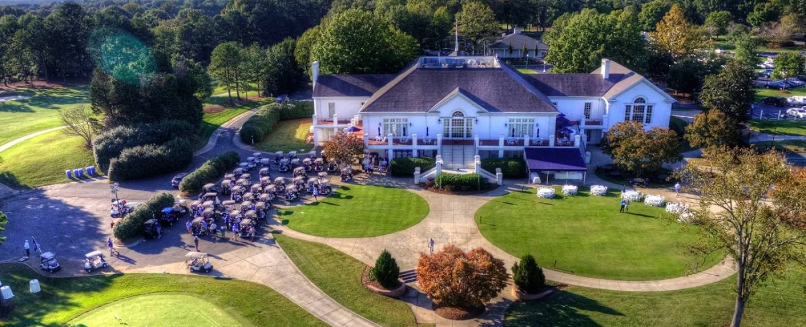 Group of professionally dressed people smiling in a modern, warmly lit room with art and chairs.