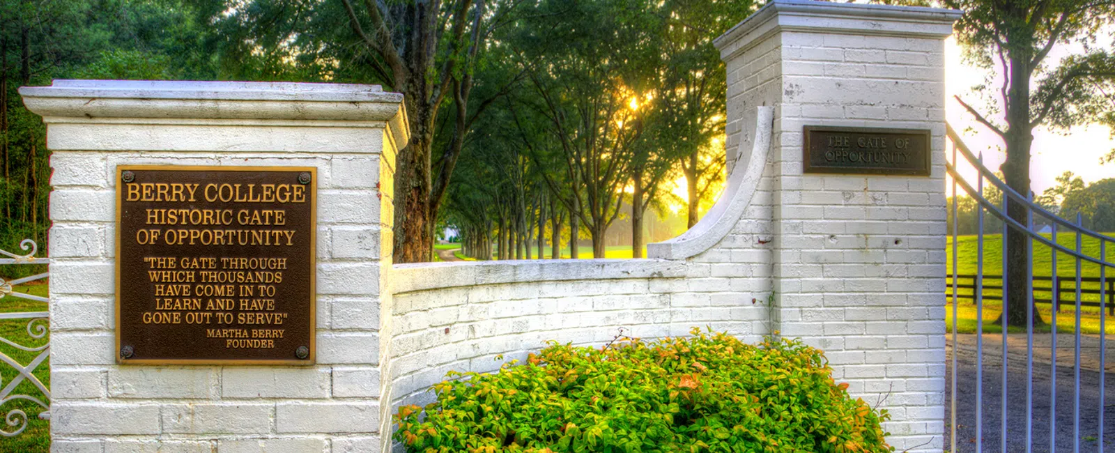 Berry College's Historic Gate of Opportunity at sunrise, showcasing scenic trees and inviting entrance.