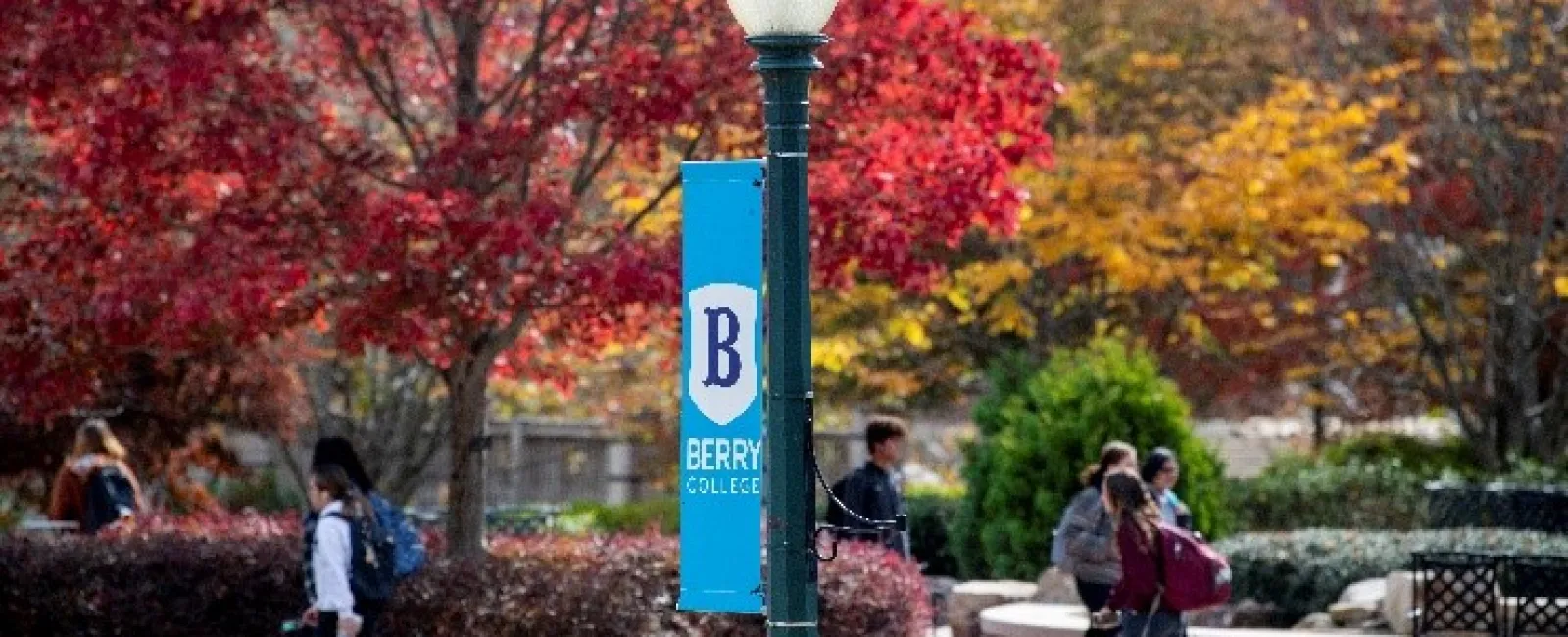 Berry College Logo on a Lamp Post in Front of Fall-Colored Trees