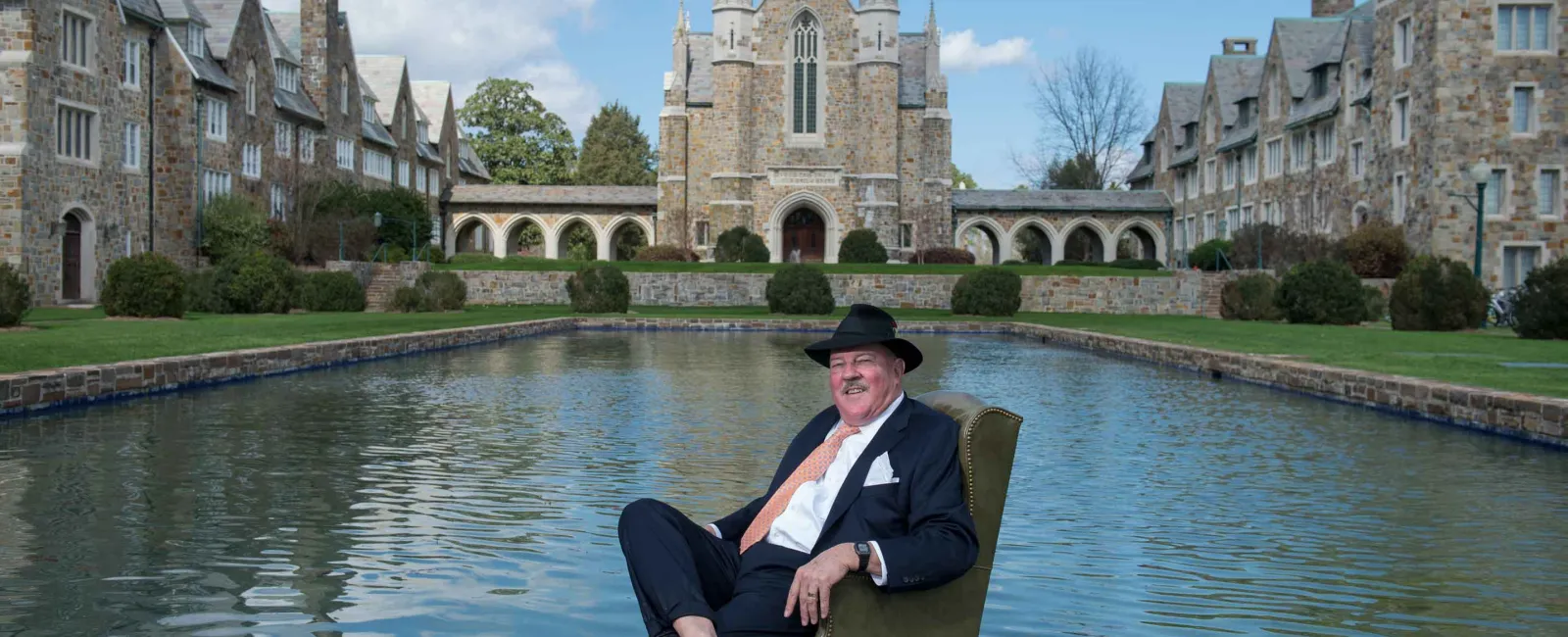 Berry alumnus sits in a chair in the reflecting pool in front of the Ford Buildings