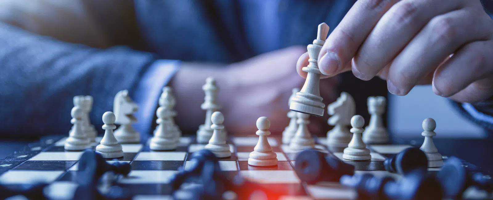 Hand moving white king chess piece on board during game focusing on strategy and concentration