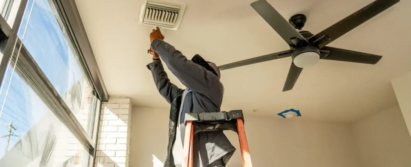 a person on a ladder painting a ceiling