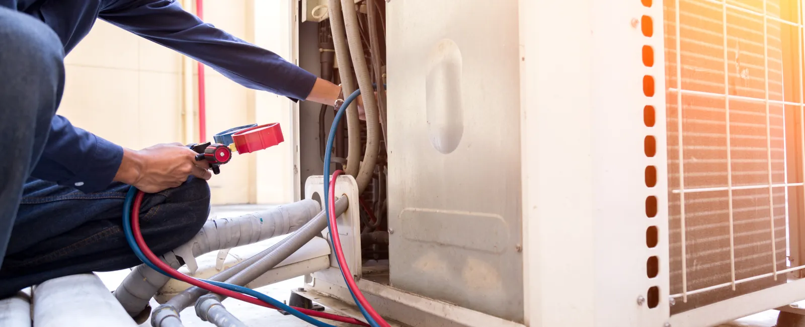 Technician inspecting and repairing an air conditioning unit with diagnostic tools in sunlight.