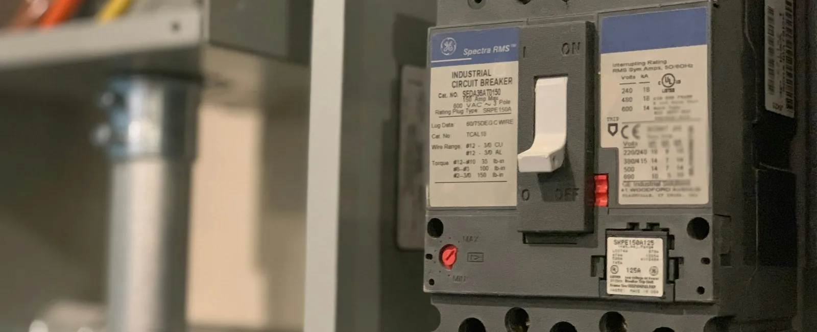 Close-up of an industrial circuit breaker with colored wiring in an electrical panel.