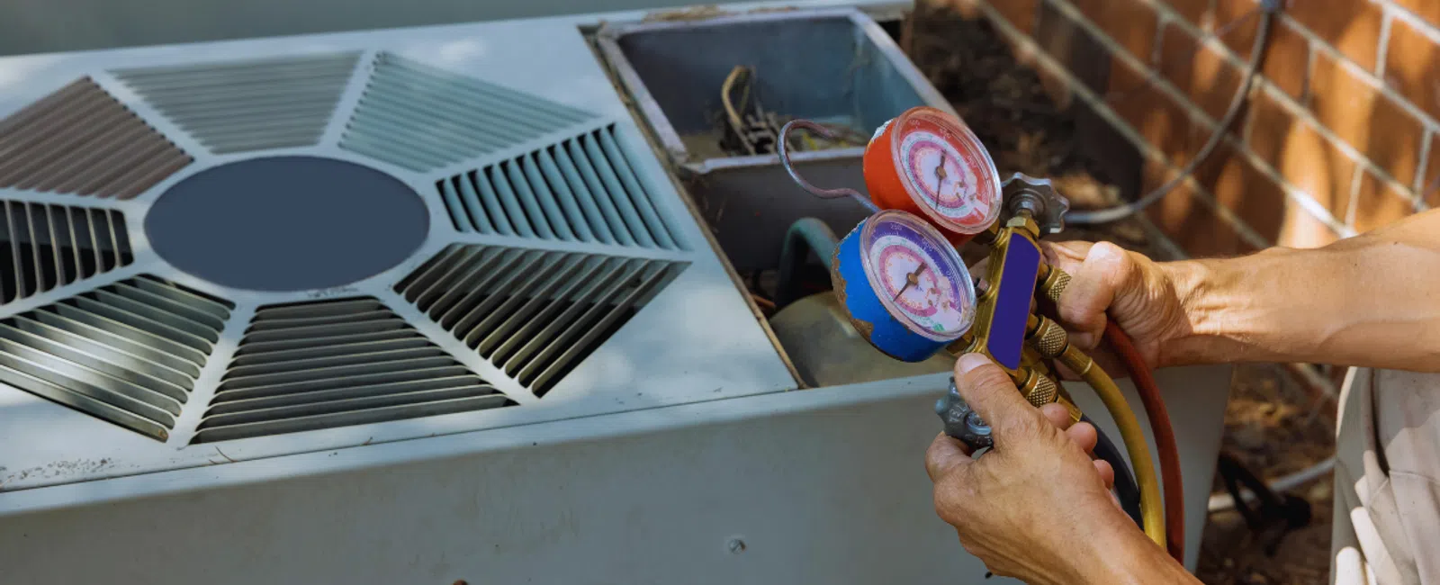 Technician testing and servicing an outdoor air conditioning unit with pressure gauges and tools.