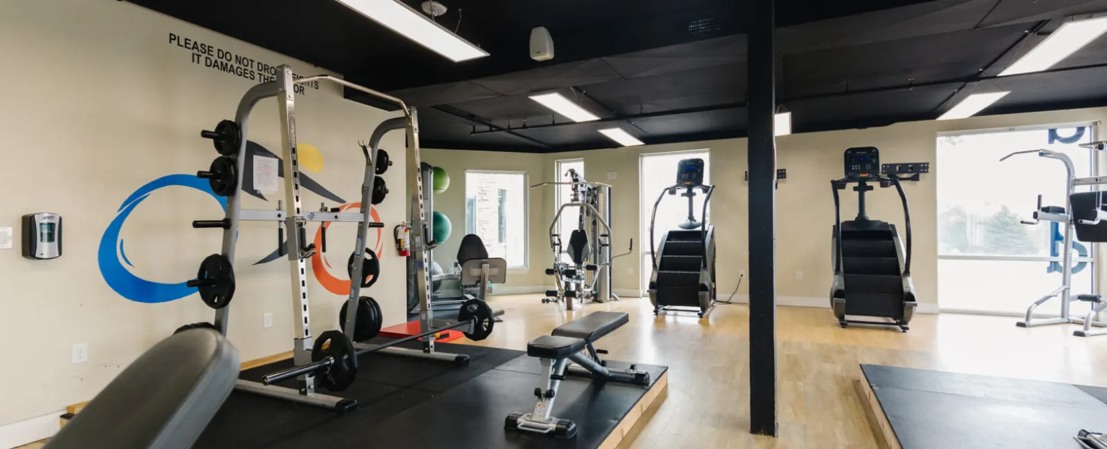 Modern gym interior featuring weight equipment, benches, and fitness machines in a spacious layout.