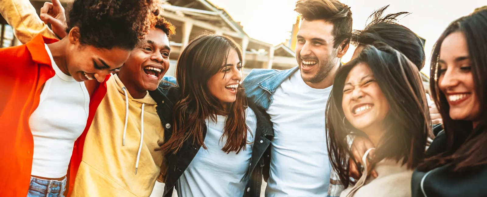 Group of diverse friends joyfully embracing outdoors, showcasing unity and happiness.