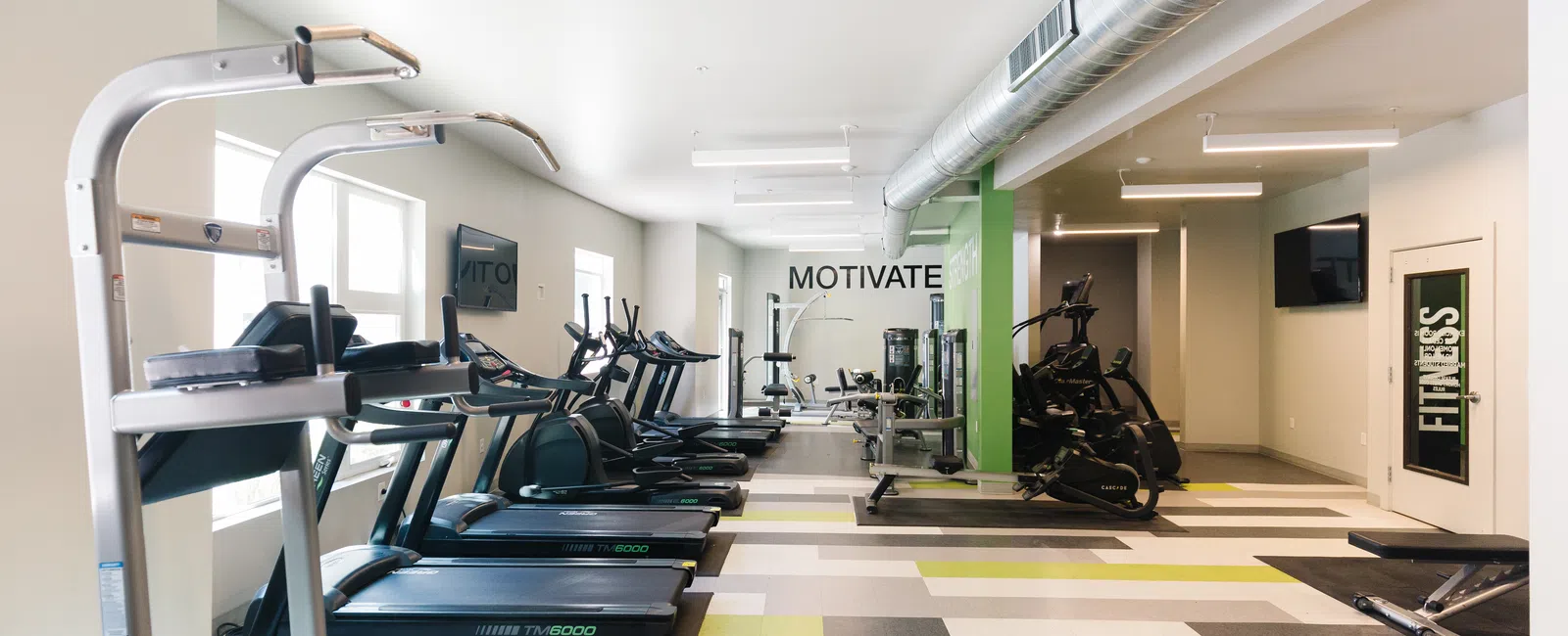 Modern gym interior featuring treadmills, ellipticals, and motivational signage.