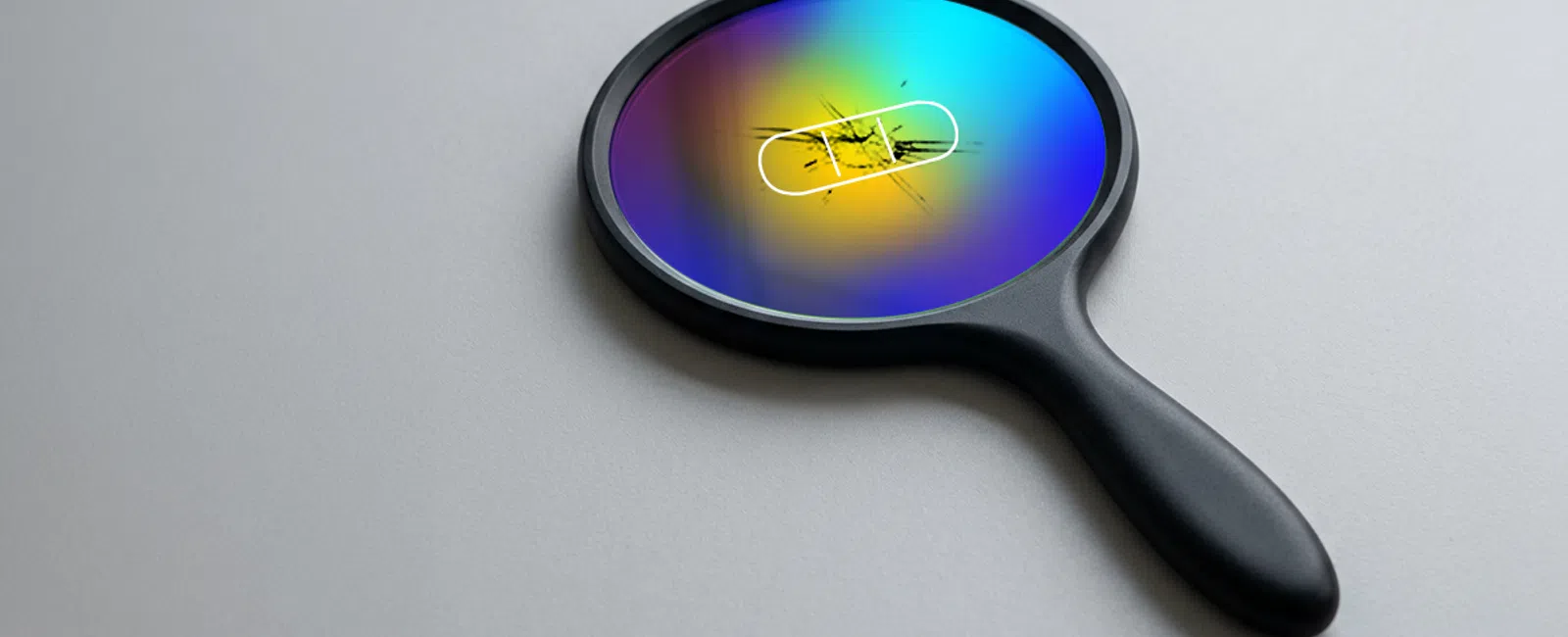 Colorful magnifying glass with scratches on a white surface, highlighting cracked glass detail.