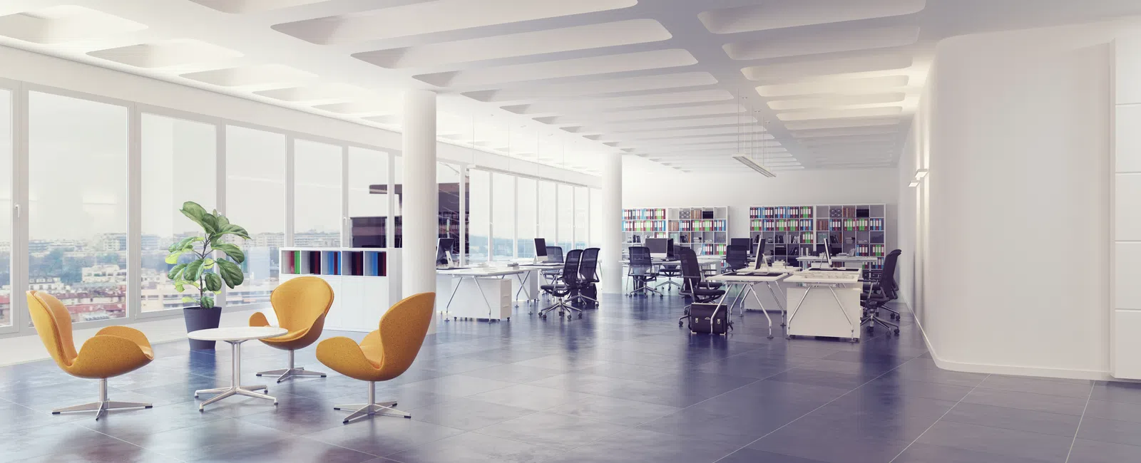 Bright modern open office space with large windows, ergonomic chairs, desks, and yellow lounge seating area.