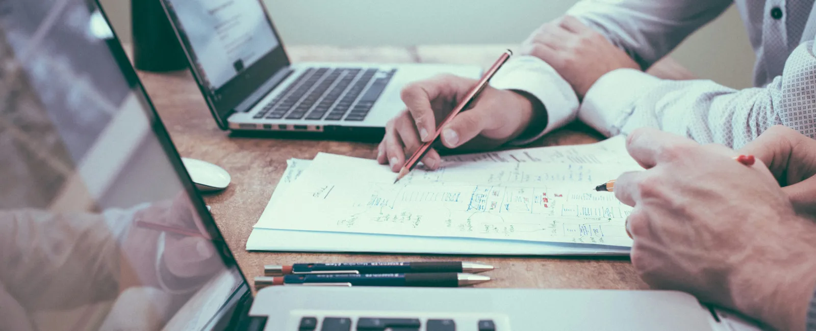 Business owner discussing managed IT strategy reviewing notes and documents at wooden desk.