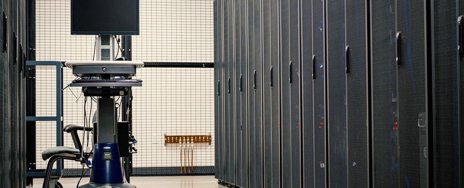 Row of server racks with a mobile workstation computer in a secure data center room.