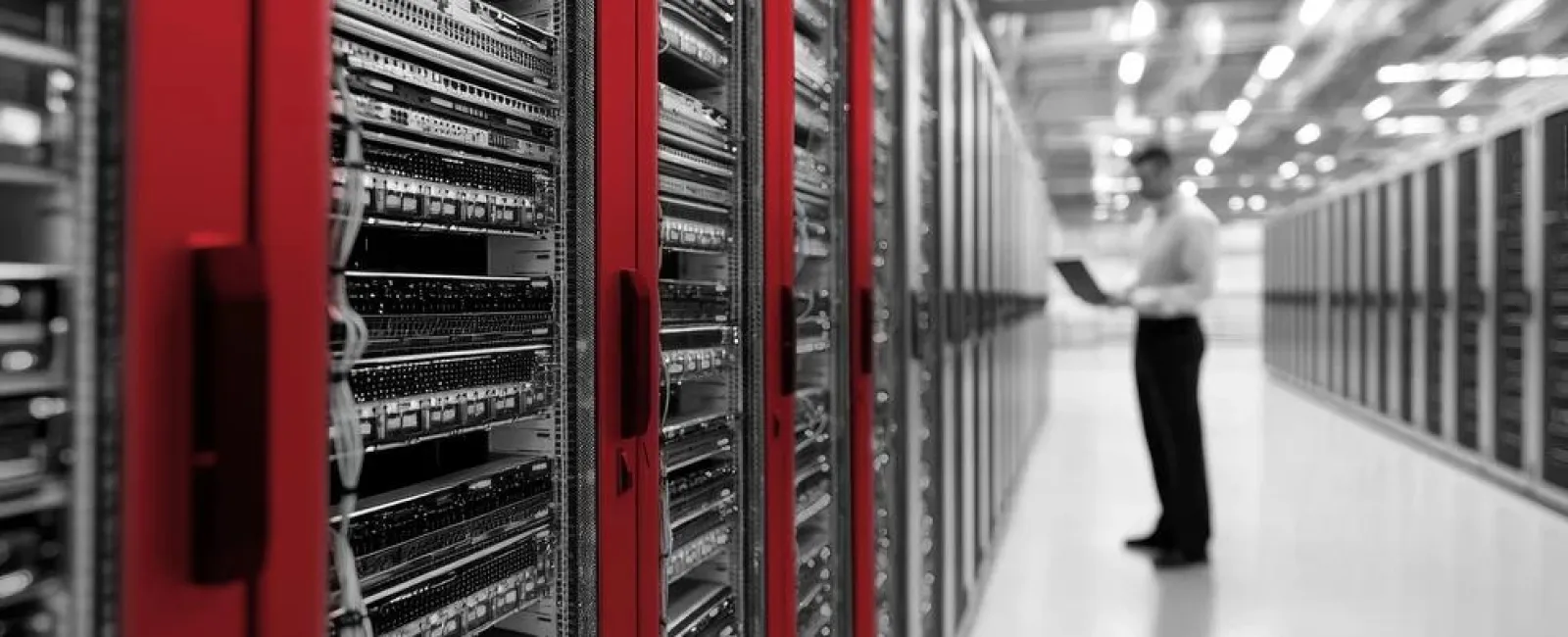 IT technician working with servers in a modern data center with red server racks and high-tech equipment.