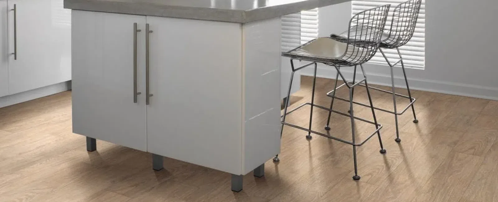 Modern kitchen island with gray countertop, white cabinets, and two metal wire bar stools on wood floor.