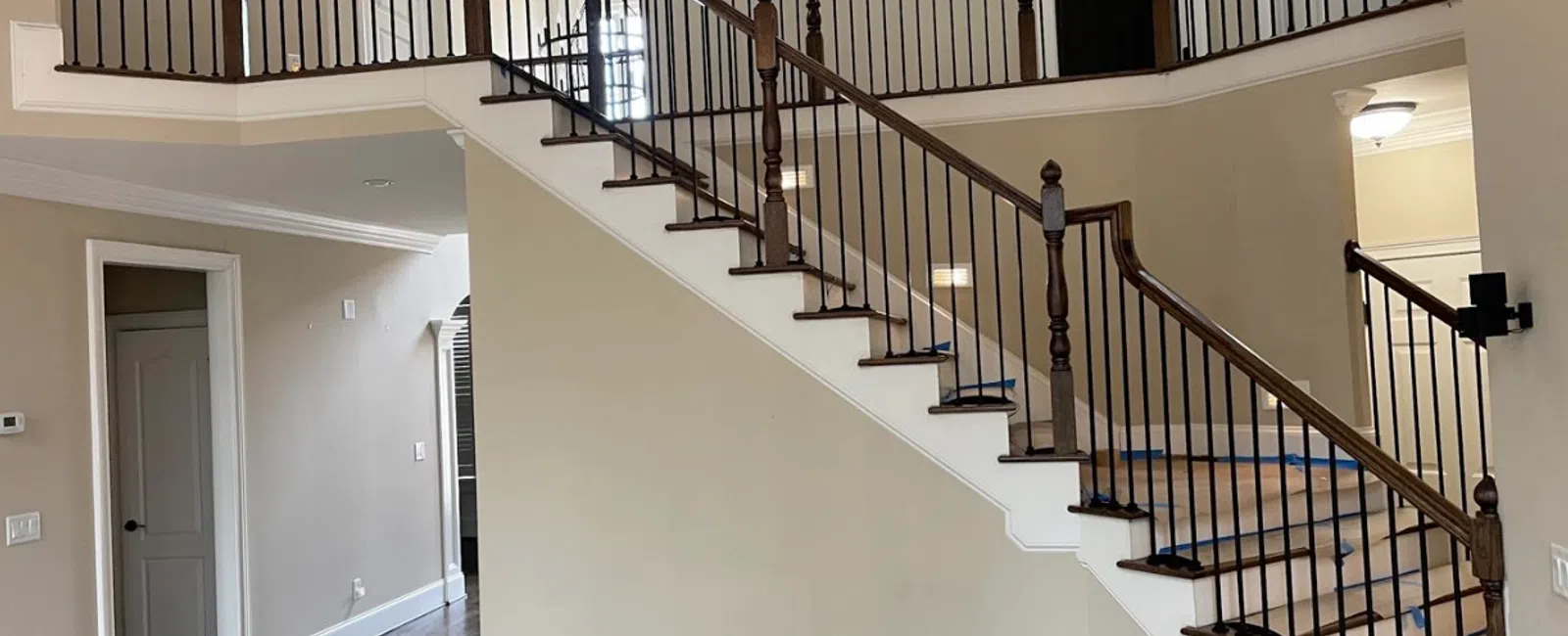Interior of a home featuring a wooden staircase with black iron balusters and hardwood flooring.