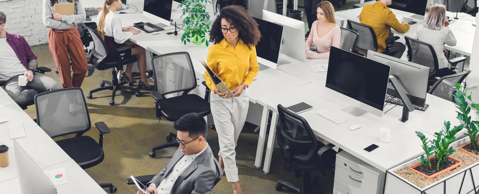 Modern open office with diverse young professionals working on computers and collaborating throughout the space