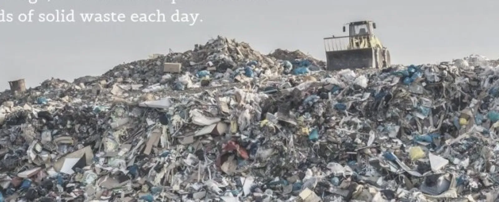 Large landfill pile with bulldozer on top managing tons of solid waste under a clear sky.