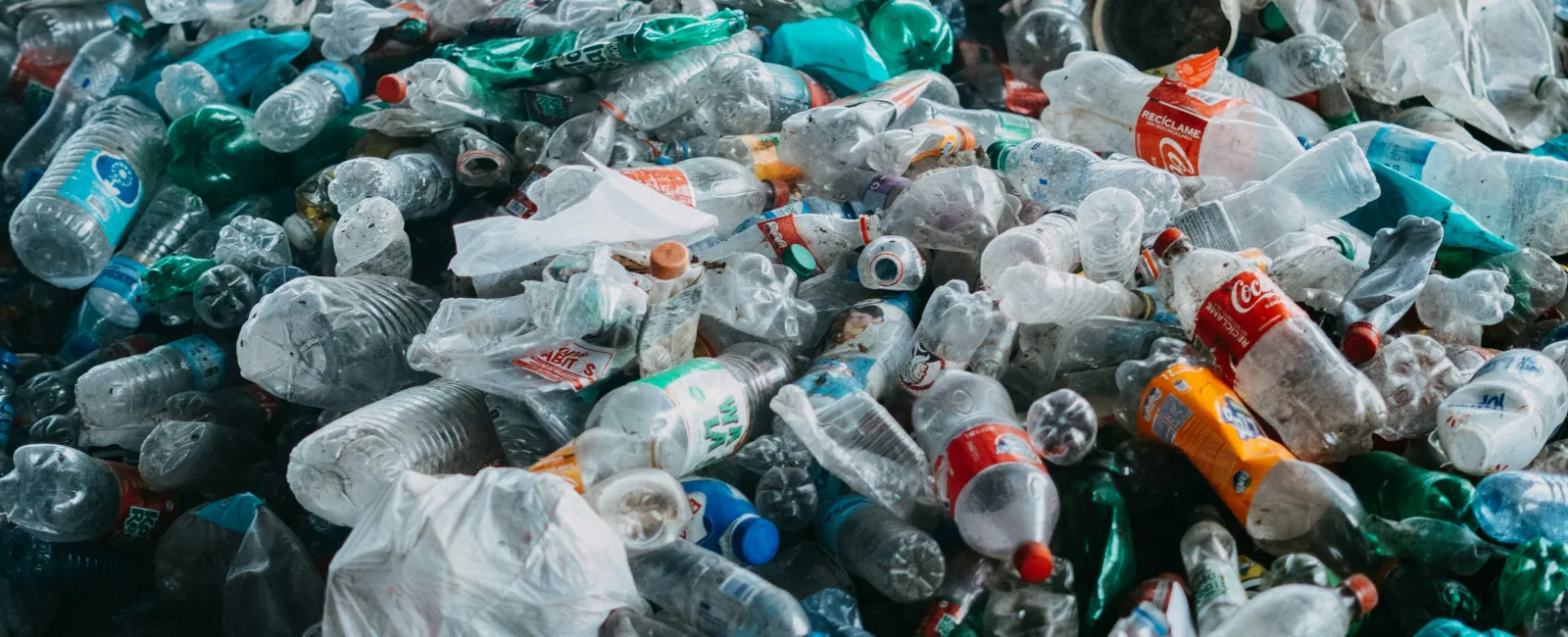 Large pile of discarded plastic bottles and containers in an outdoor setting highlighting environmental pollution.