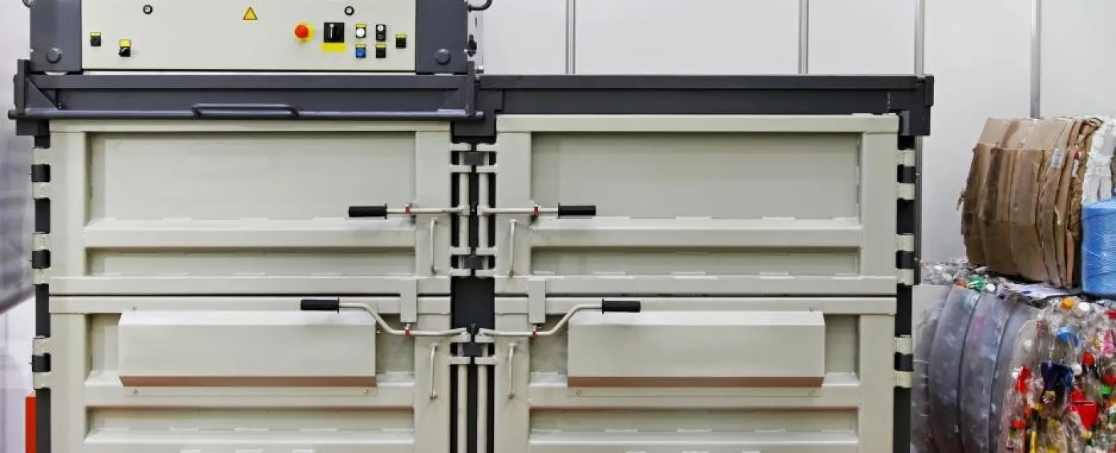 Industrial baler machine compressing recyclable waste materials in an indoor recycling facility.