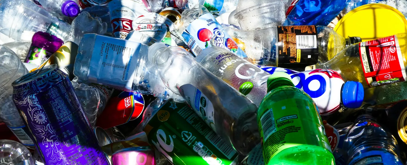 Pile of assorted empty plastic bottles and cans in bright daylight highlighting recycling waste