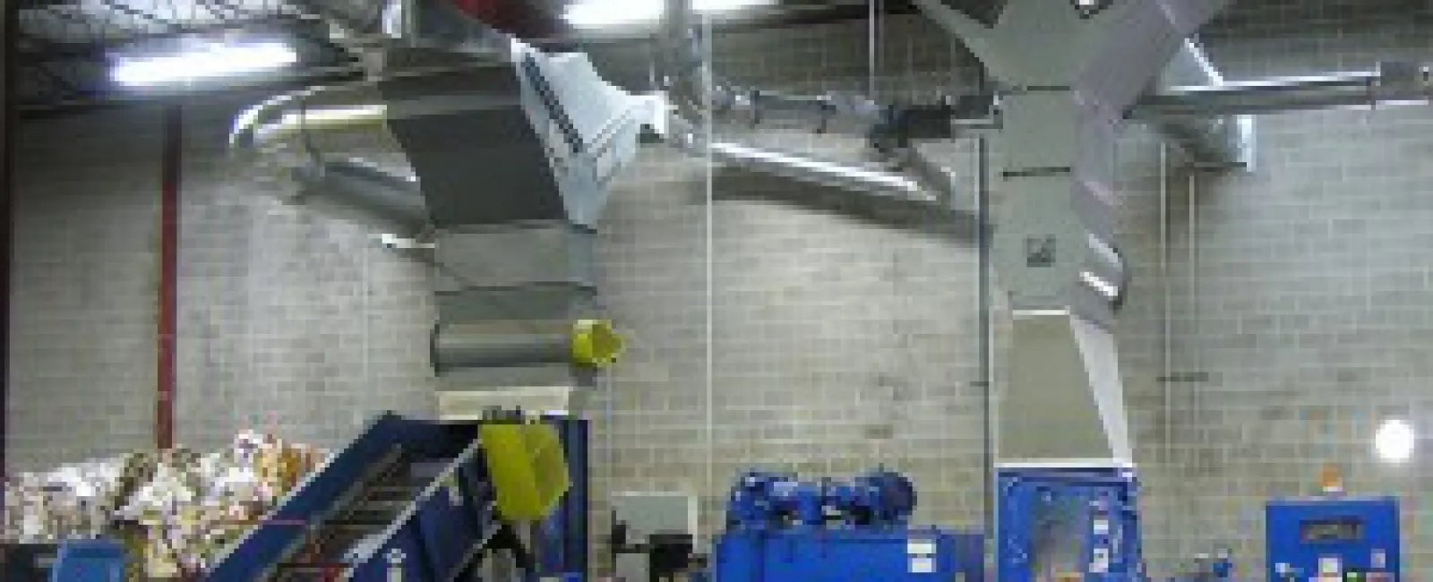 Industrial recycling facility with blue machinery and conveyor system handling paper materials indoors