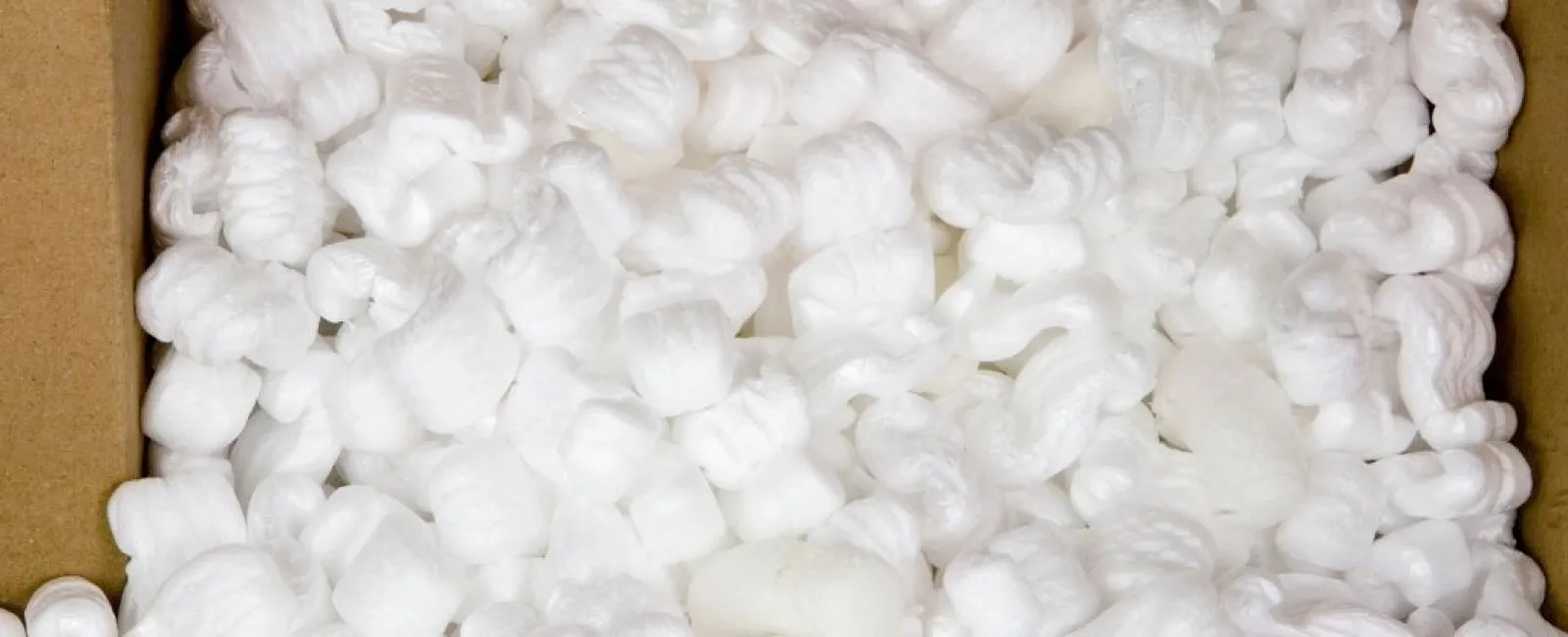 Close-up of white packing peanuts filling a cardboard box used for shipping protection and cushioning.