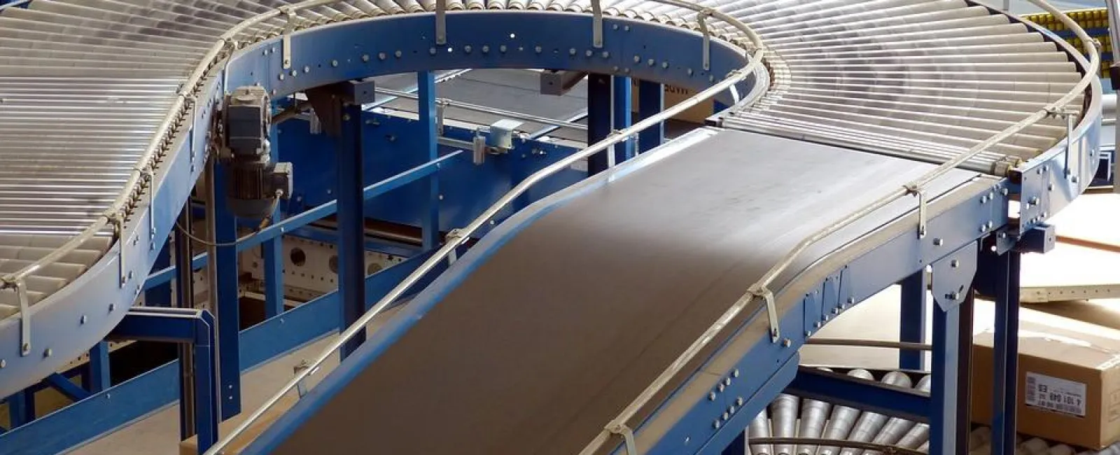 Curved industrial conveyor belts and rollers in a warehouse for material handling and packaging processes.