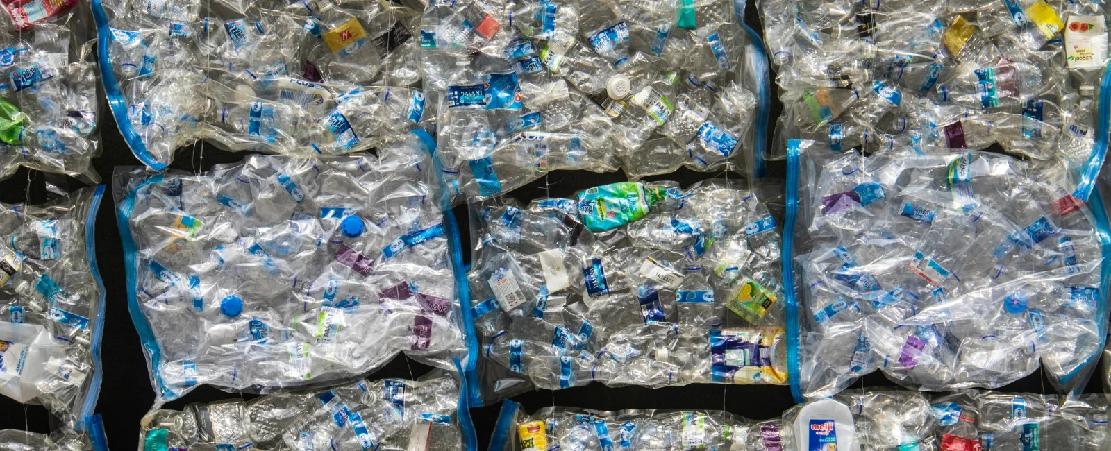 Stacks of crushed plastic bottles packed tightly in rectangular bales ready for recycling processing.