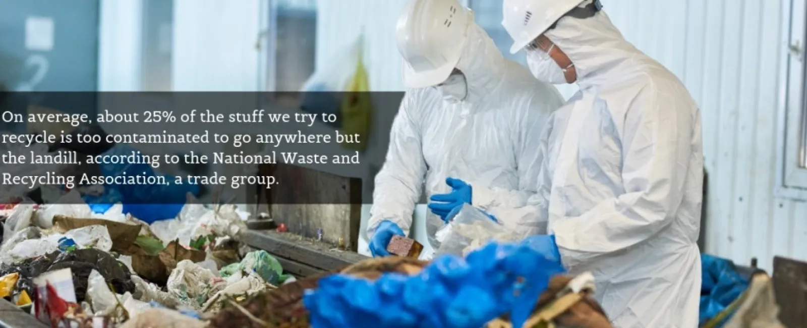 Workers in protective suits and helmets sort contaminated recyclables on a conveyor belt at a waste facility.