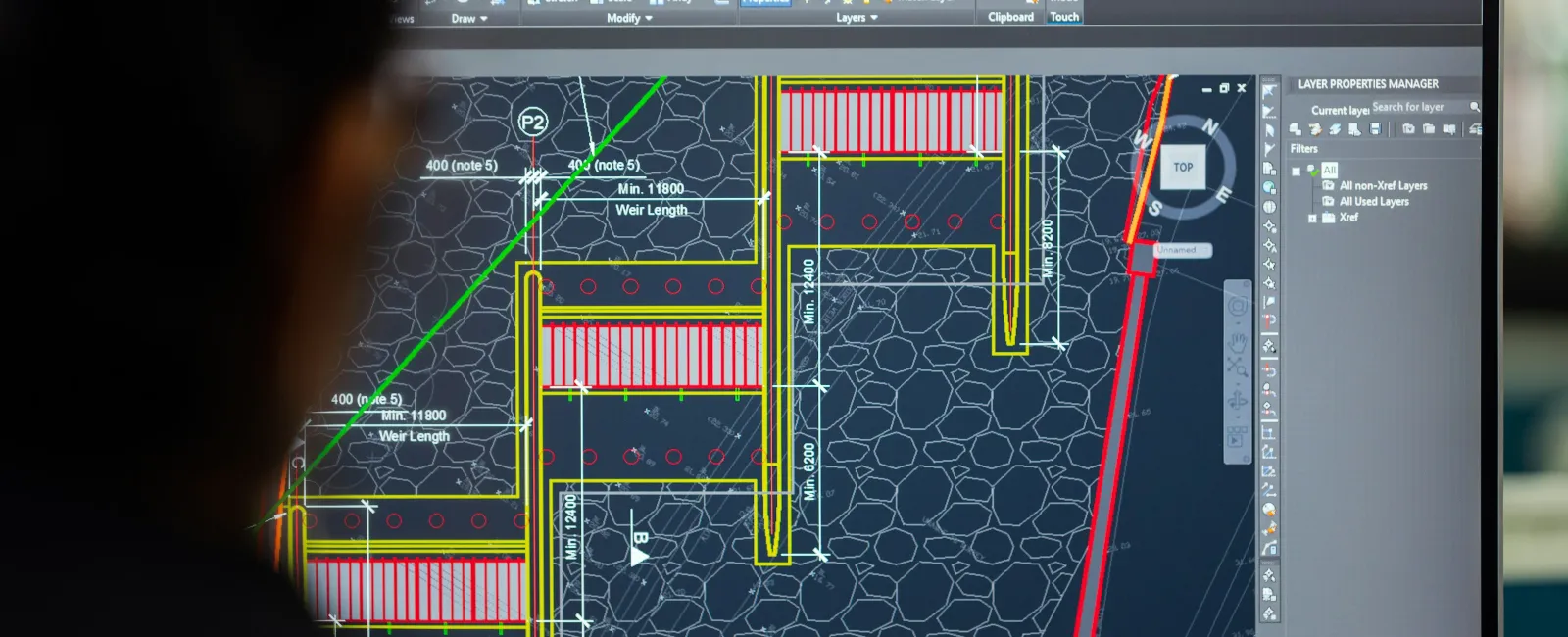 Engineer viewing detailed architectural blueprints on a computer screen in CAD software interface.