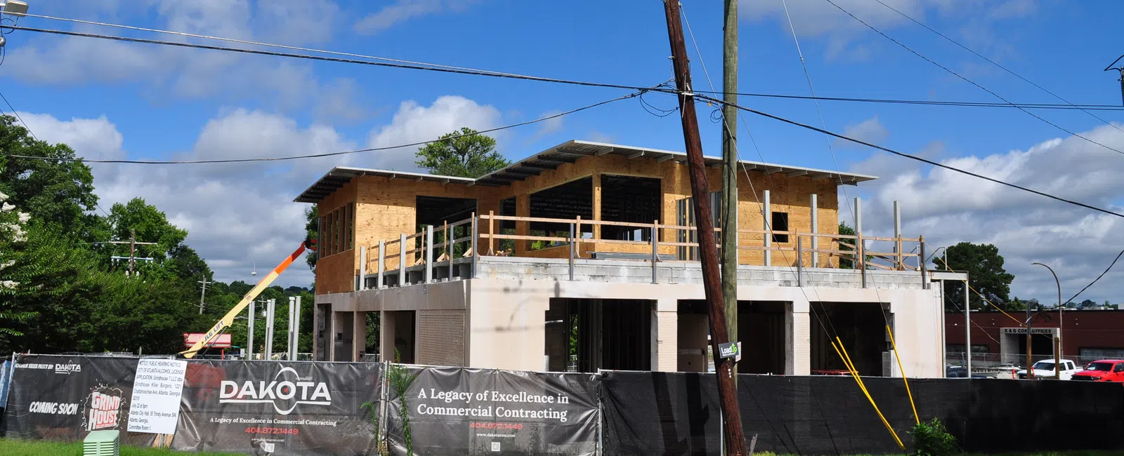 Two-story commercial building under construction with wooden framing and Dakota contracting signage on fencing.