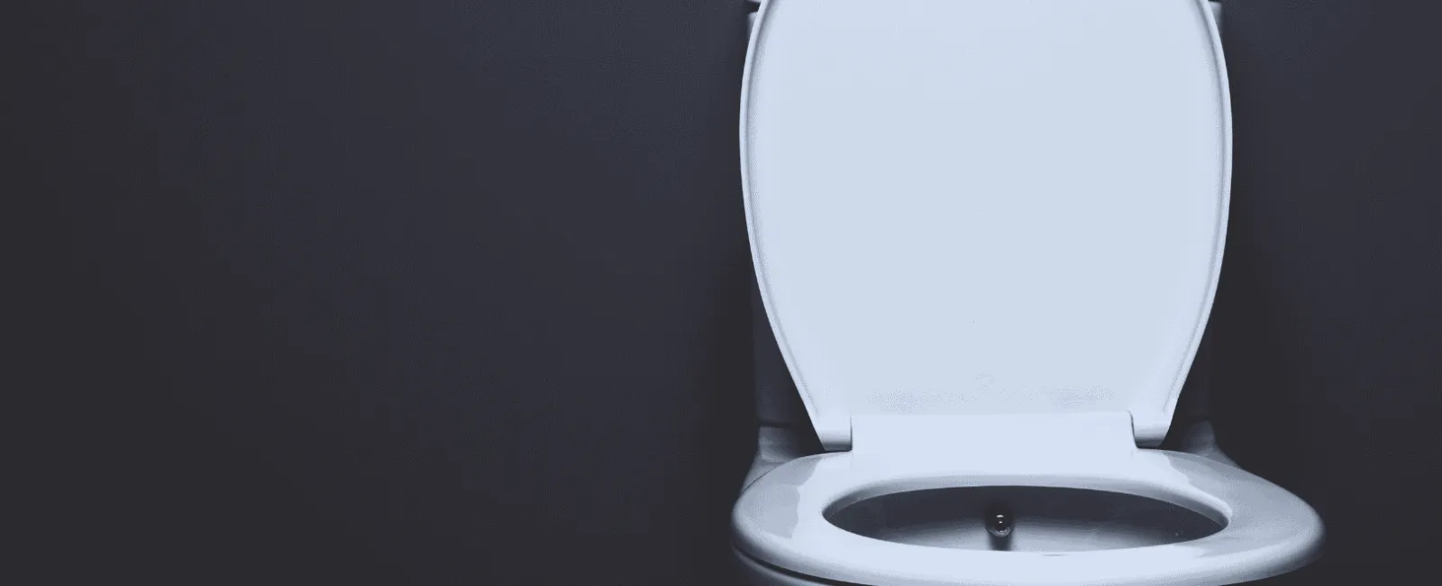 White toilet with open lid against a dark gray background in a minimalist bathroom setting