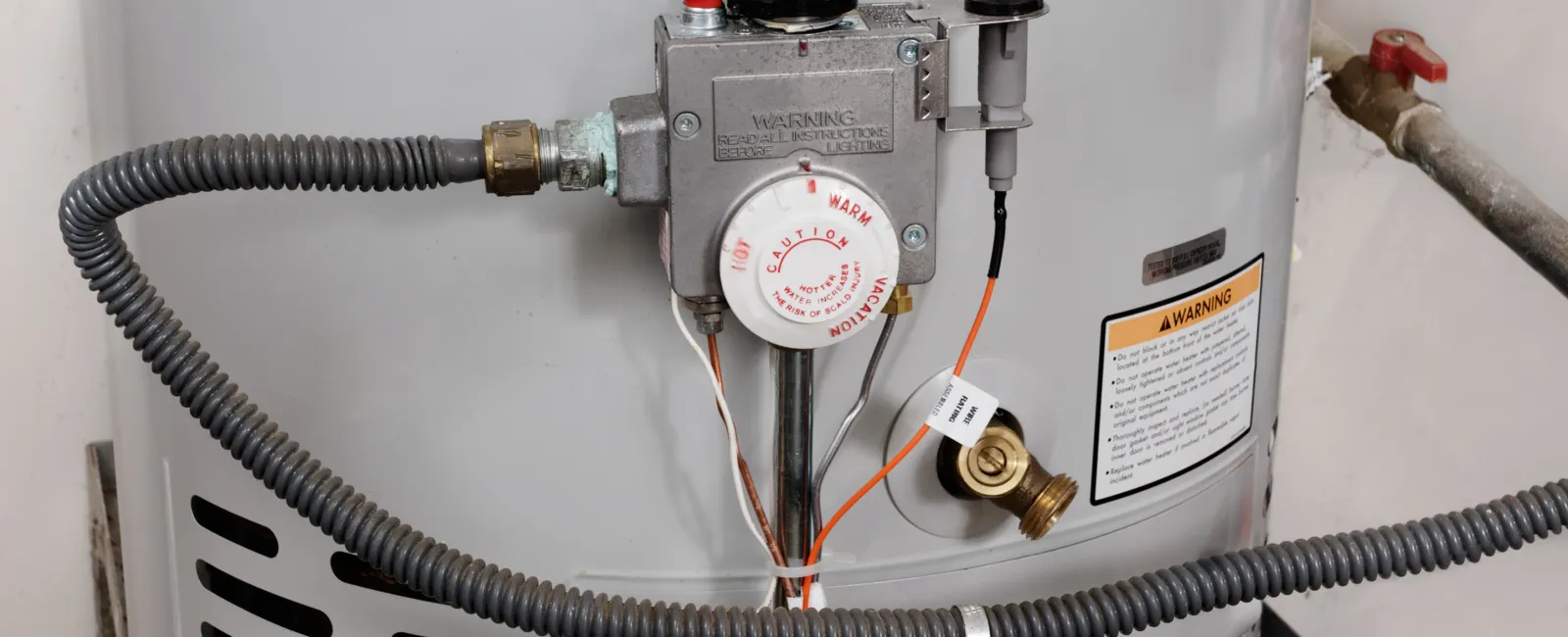 Close-up of a water heater with plumbing and safety features clearly visible.