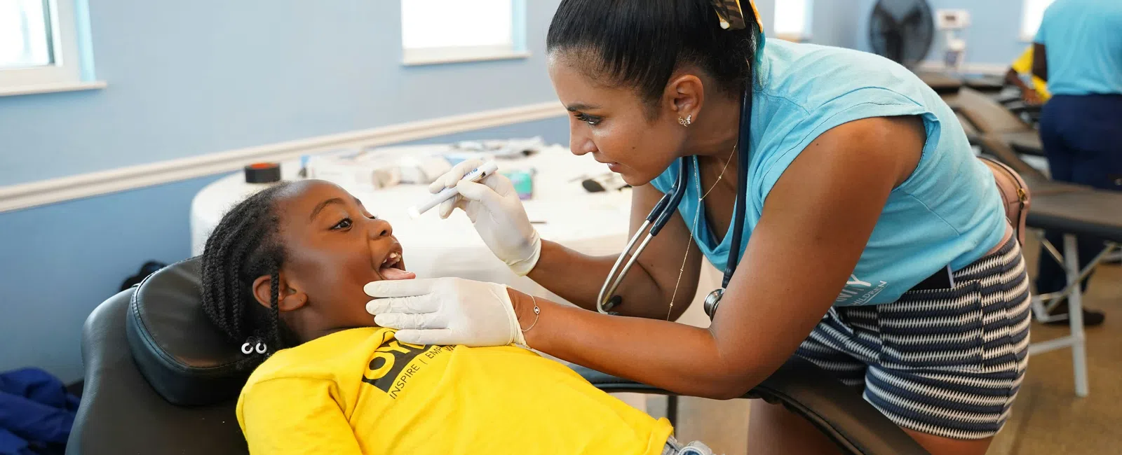 Healthcare professional examines young girl’s throat during medical checkup in bright clinic room