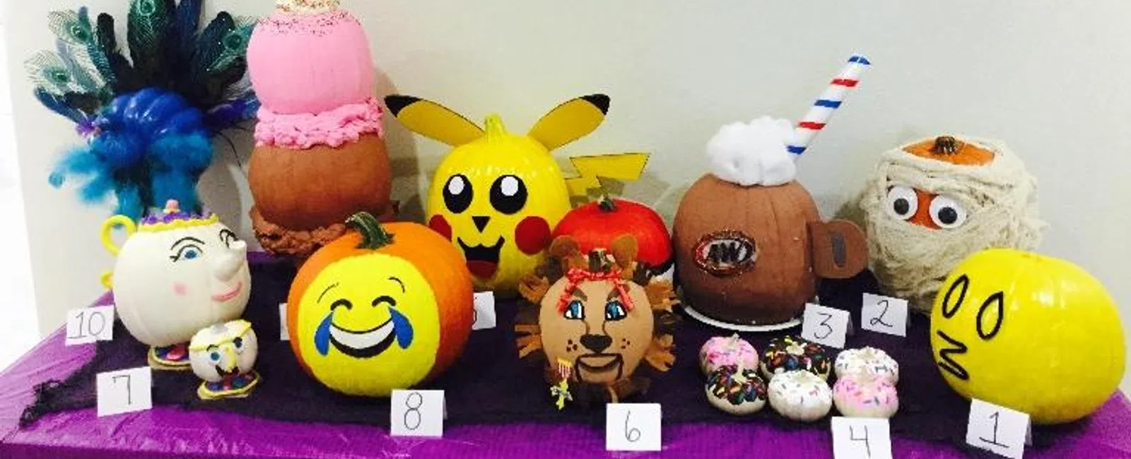 Decorated pumpkins including Pikachu, emojis, and characters displayed at Burleson pediatric dentistry event.