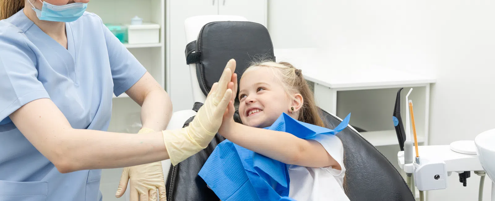 Child patient giving a high-five to a smiling female dentist in a dental clinic