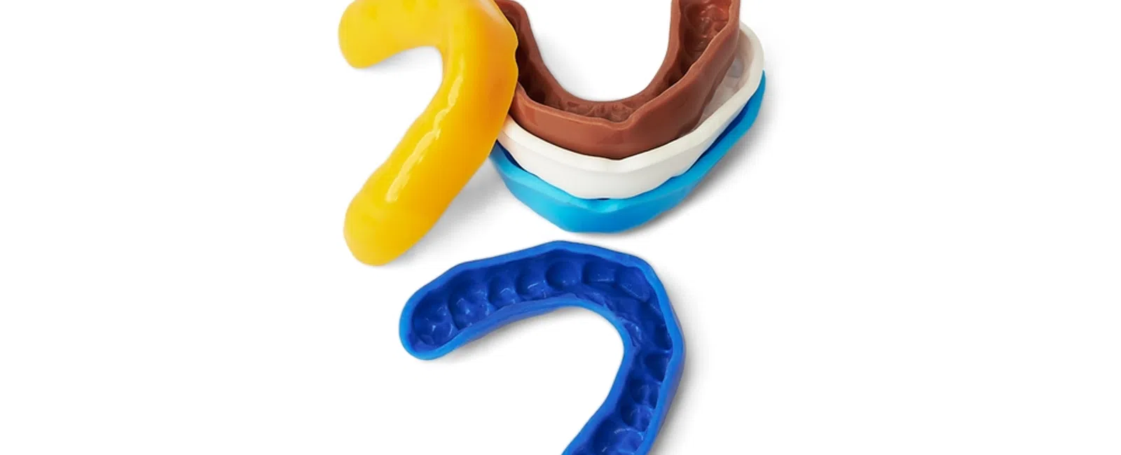 Various colored dental impression trays and molds used for taking teeth impressions on white background