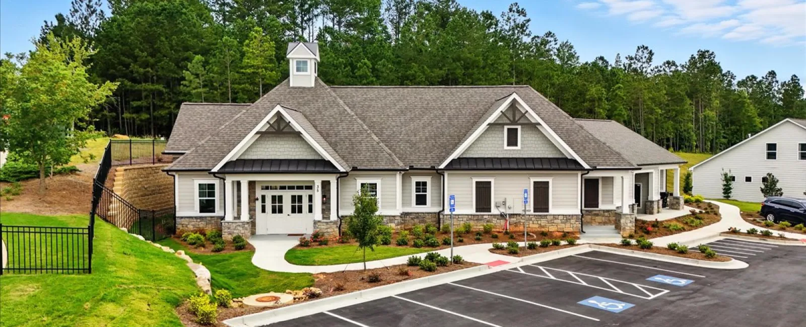 Community center building with stone accents, surrounded by trees and a parking lot with handicap spaces.