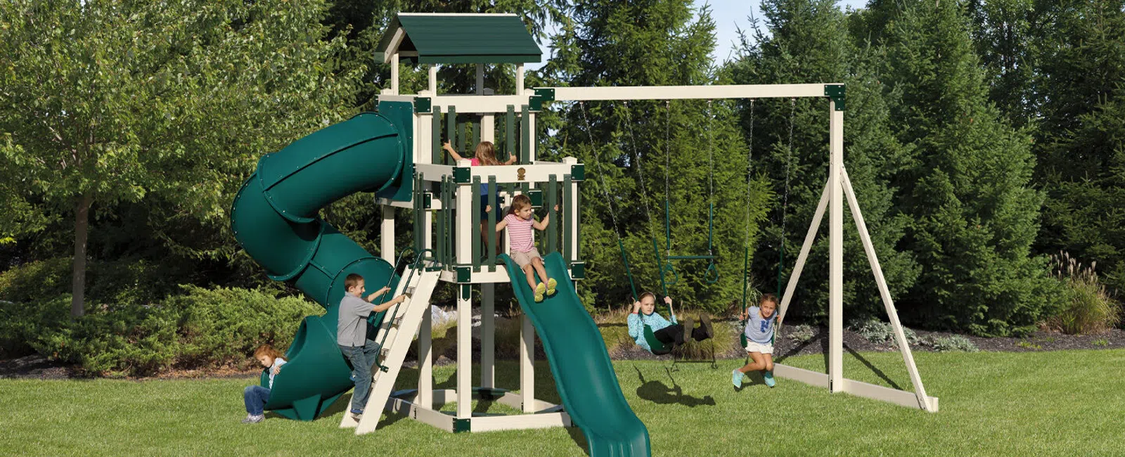 Children playing on a green and beige backyard playground with slides, swings, and climbing features on a sunny day.