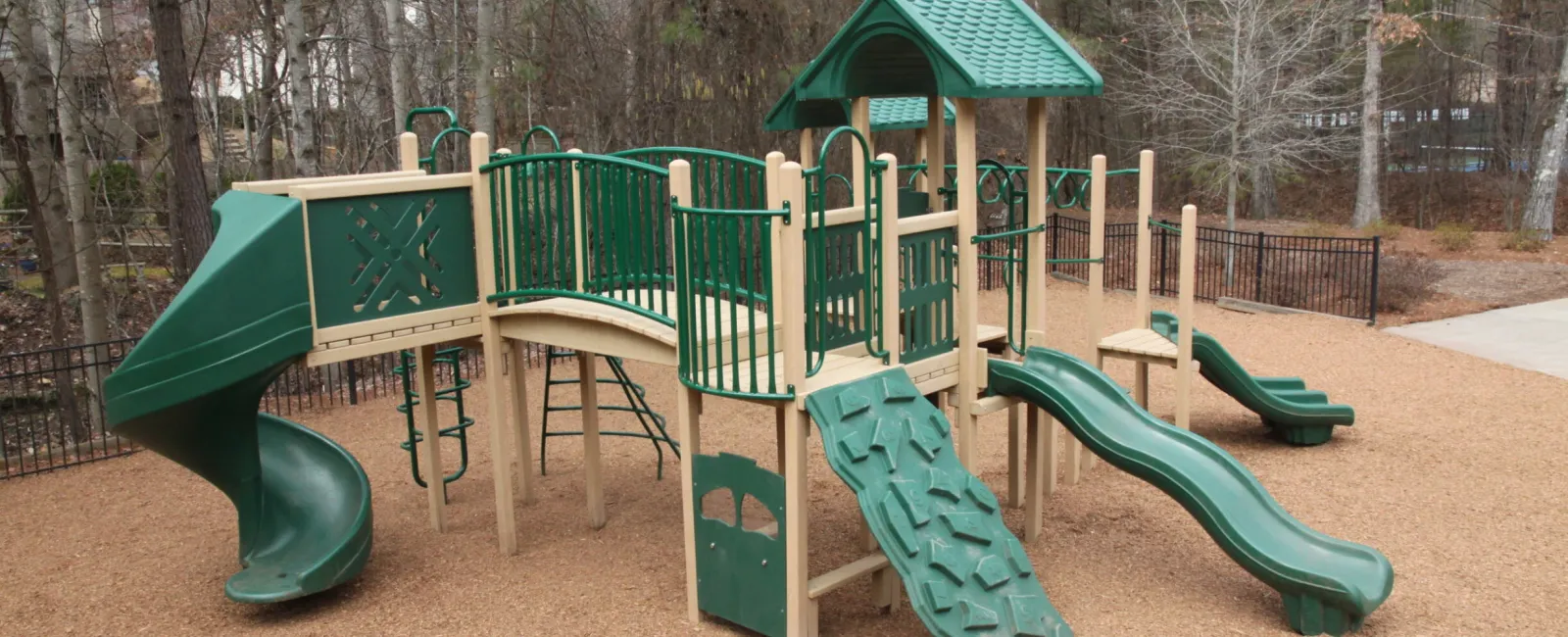 a playground with green slide and trees