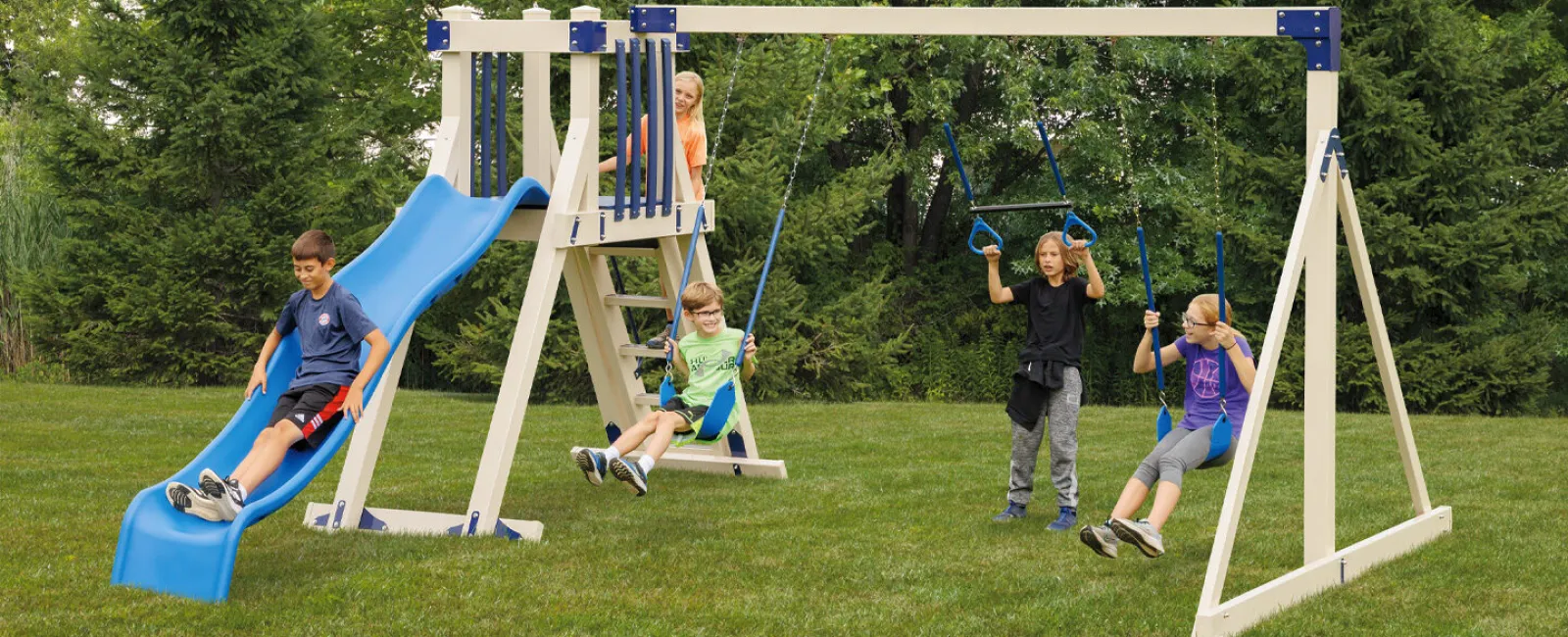 Children playing on a backyard swing set with a slide and climbing structure in a grassy yard.